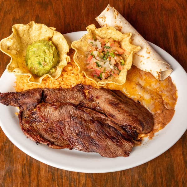 Grilled steak with rice, refried beans, guacamole, pico de gallo in tortilla bowls, and a tortilla.