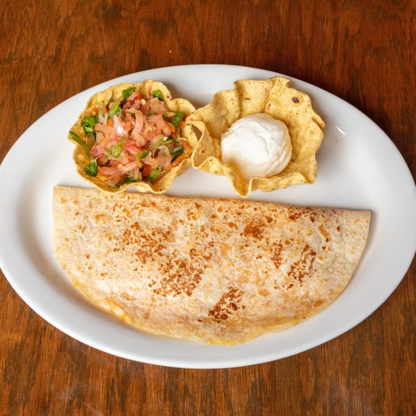 A quesadilla with pico de gallo and sour cream in tortilla bowls on a white plate.