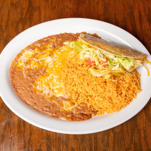 A white plate with a crispy taco, refried beans with melted cheese, and orange Spanish rice.